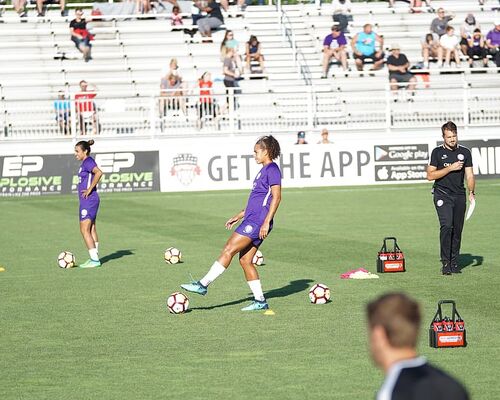 two-woman-standing-on-green-soccer-field